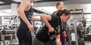 Three women lift weights at The Ray at DePaul University