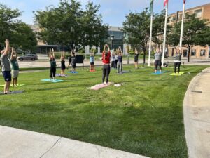Group of people in workout attire practice yoga outdoors at CSU.