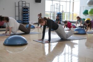 College age woman in yoga class executes a stretch.