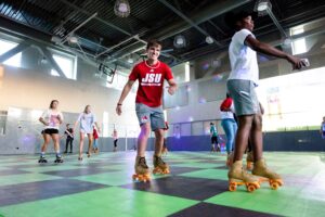 A student roller skating inside the Jacksonville State University Recreation Center during an event, showcasing how student life facilities support vibrant, well-operated campus spaces.