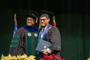 Cleveland State University graduate receives a diploma on stage during commencement at the Wolstein Center.