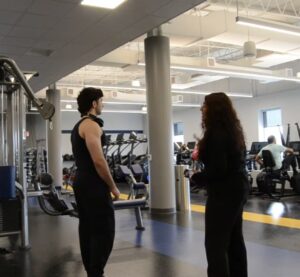 Preeti Thakkar explains filming directions to a student extra on the Harper College Recreation workout floor.