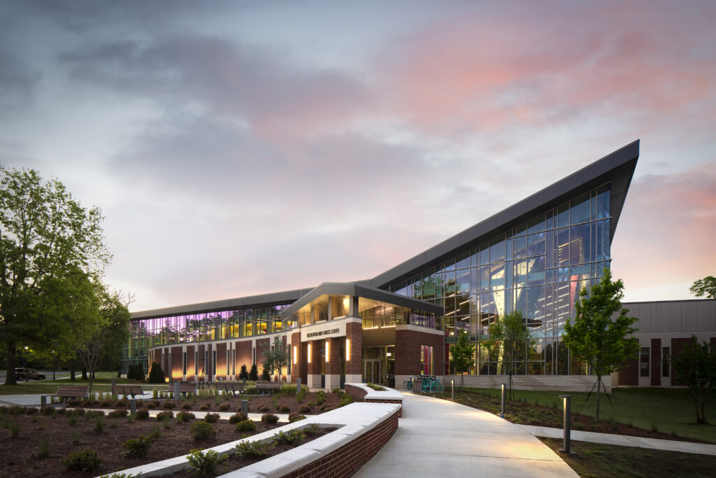 Exterior of the Jacksonville State University Recreation and Fitness Center at golden hour, with warm evening light illuminating the building façade and surrounding campus landscape.