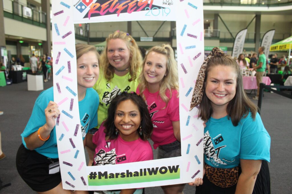 Five members of the Marshall University recreation marketing team pose in a RecFest photo frame during a campus engagement event.